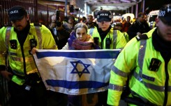 Police officers escort a woman with an Israeli flag away from Pro-Palestinian protesters outside Villa Park in Birmingham on November 6, 2025 ahead of the UEFA Europa League league-stage football match between Aston Villa and Maccabi Tel Aviv