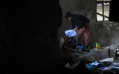 A Palestinian girl picks up her school work from the debris of a destroyed house