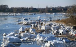 Onlookers make their way through large chunks of ice washed up along the banks of the Elbe river near Geesthacht, northern Germany, on January 19, 2026.
