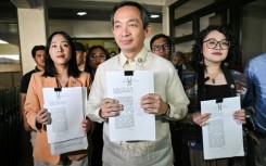 Lawmakers Sara Elago, Antonio Tinio and Louise Co show the impeachment complaint against Philippine President Ferdinand Marcos at the House of Representatives on Thursday