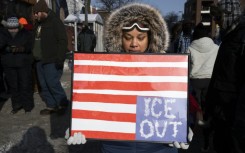 A woman holds a placard with an upside down American flag to protest violence by the ICE immigration agency in Minneapolis