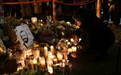 A woman lights a candle while mourning at a memorial where Alex Pretti was shot dead by federal immigration agents in Minneapolis