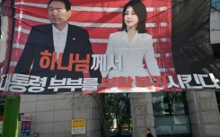 A man walks past a banner showing a picture of South Korea's former impeached president Yoon Suk Yeol and his wife Kim Keon Hee