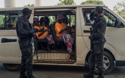 Security officers stand guard next to a bus carrying freed worshippers in northern Nigeria, where gunmen kidnapped Christians in coordinated attacks on three churches in January