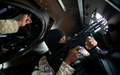 A Haitian police officer aims his weapon out a window of an armored vehicle during a patrol in downtown Port-au-Prince in January 2026