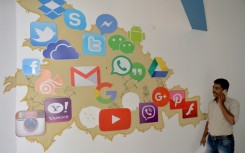 A man passes by a mural depicting various social media apps in Bangalore on March 22, 2018