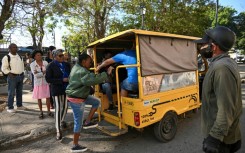 People line up to board an electric tricycle on a street in Havana