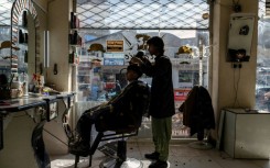 An Afghan barber attends to a customer at a salon in Kabul