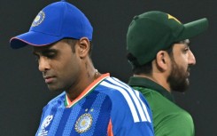 India's captain Suryakumar Yadav (L) walks past his Pakistan counterpart Salman Agha after the toss