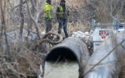 Emergency workers look on as raw sewage flows out of a drainage pipe into the C&O Canal near Cabin John, Maryland, after more than 200 million gallons of wastewater spilled into the Potomac River