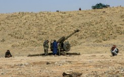 Afghan security personnel stand next to an artillery gun near the border with Pakistan, whose defence minister said both countries were at 'open war'
