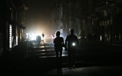 People walk on a street without power during a nationwide blackout in Havana on March 21, 2026