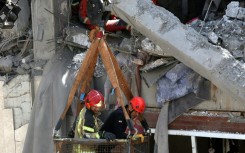 Firefighters try to recover the body of a victim in a damaged building in southern Tehran