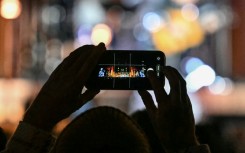 A fan takes photos at an event in London to mark the 50th birthday of US tech giant Apple