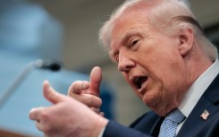 US President Donald Trump mimics firing a gun as he speaks in the White House about the war against Iran