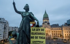 A Greenpeace activist unfurls a banner reading 'Hands off the Glaciers Law' outside Argentina's parliament ahead of a vote by MPs on an amendment watering down glacier protections