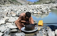 An Afghan man scours for gold using the traditional gold-panning technique allowed by authorities