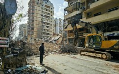 A bulldozer clears the rubble from the site of an Israeli airstrike as people return to Beirut's southern suburbs