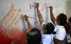 Esmeralda Rosales writes a message addressed to her missing brother, Fernando Rosales, during the inauguration of a mural in tribute to disappeared people, at the University of El Salvador, in San Salvador, on March 19, 2026