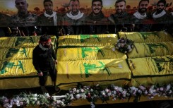 Coffins sit on a trailer beneath portraits of Hezbollah fighters killed in Lebanon by Israel before a 10-day ceasefire was agreed