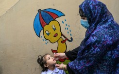 A healthcare worker administers polio drops during a door-to-door poliovirus eradication campaign in Lahore