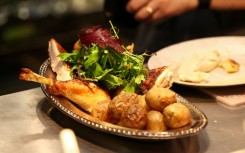 A cook prepares a rotisserie chicken with potatoes during dinner in the French restaurant Gigi’s in the Brooklyn borough of New York City on April 26, 2026
