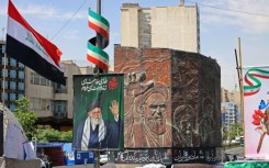 Commuters make their way past a picture of Iran's slain supreme leader Ayatollah Ali Khamenei (L) and a sculpture of late supreme leader Ayatollah Ruhollah Khomeini in Tehran