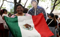 Una mujer muestra una bandera de México junto a una figura de cartón de J-Hope, cantante surcoreano de K-pop del grupo BTS, durante una reunión de fans en la Ciudad de México el 3 de mayo de 2026.
