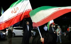 Women hold Iran's national flags during an anti-US and Israel protest in Tehran