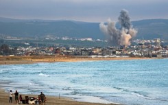 People visit beach against the backdrop of smoke rising from the site of an Israeli strike near the southern Lebanese city of Tyre on May 27
