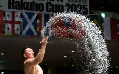 Sumo wrestlers throw salt on the dohyo to drive away evil spirits