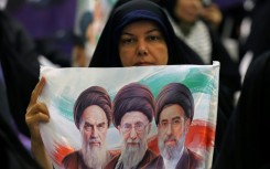An Iranian woman holds an image of the former and current Iranian supreme leaders in Tehran