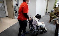 A caretaker wheels an elderly woman after a bath at a day care facility for senior citizens in Tokyo