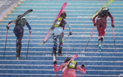 Competitors race uphill in a women's sprint ski mountaineering heat during the Milano Cortina 2026 Winter Olympic Games