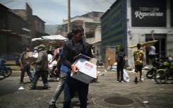 A man carries a box as looting erupted in Catia La Mar in La Guaira State, about 30 km northwest of Caracas, on June 25, 2026