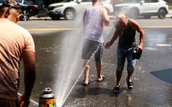 Men cool off at a fire hydrant in the Hamilton Heights neighborhood in Manhattan