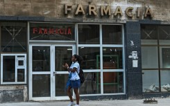 A woman walks past a pharmacy in Havana, where Cuba's communist authorities have announced an opening of sectors of its economy such as petrol stations, medicine sales and electricity generation to the private sector