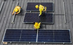 Workers instal solar panels on a roof in Carmona, in the Philippine province of Cavite