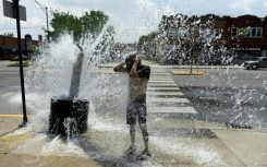A person cools off with water from an open fire hydrant during a heat wave on the West Side of Chicago, Illinois; Human-caused climate change can amplify El Nino's associated effects because a warmer ocean and atmosphere increase the availability of energy and moisture for extreme weather events