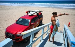 Los Angeles County lifeguard Maximus Oberto gestures as he monitors swimmers in the Pacific Ocean in Manhattan Beach