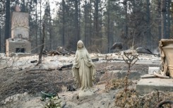 A Virgin Mary statue remains untouched in front of a burned out residential home in the Balboa neighborhood of Spokane, Washington, on August 2, 2026.