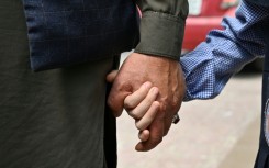 An Afghan father holds his daughter's hand