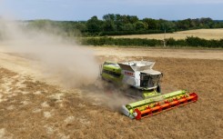 Dust clouds form around a combine harvester at Shimpling park farm in eastern England as it harvests a crop in a parched field