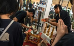 Dozens of bereaved students, parents and teachers queued at a Buddhist temple in Thailand to pray over the body of a 12-year-old girl, one of eight victims of a home and school shooting.