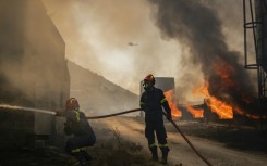 Firemen battling a blaze that broke out at a livestock facility near Kouvaras, south of Athens