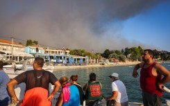 People use small boats to flee a wildfire near the village of Siviri, northern Greece