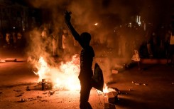 A demonstrator stands next to a burning barricade during a protest over The Gambia's electricity crisis