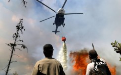 A helicopter drops water on a forest fire in central Colombia