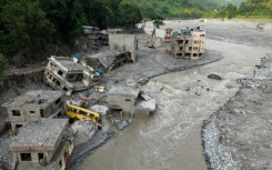 A torrent of muddy water surges past houses in the aftermath of flash floods in Nepal's Nuwakot district on August 29, 2026
